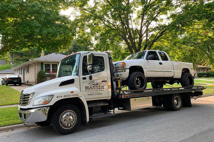 Pickup truck being towed on a flatbed tow truck in Grand Rapids, MI by Hansen Towing.