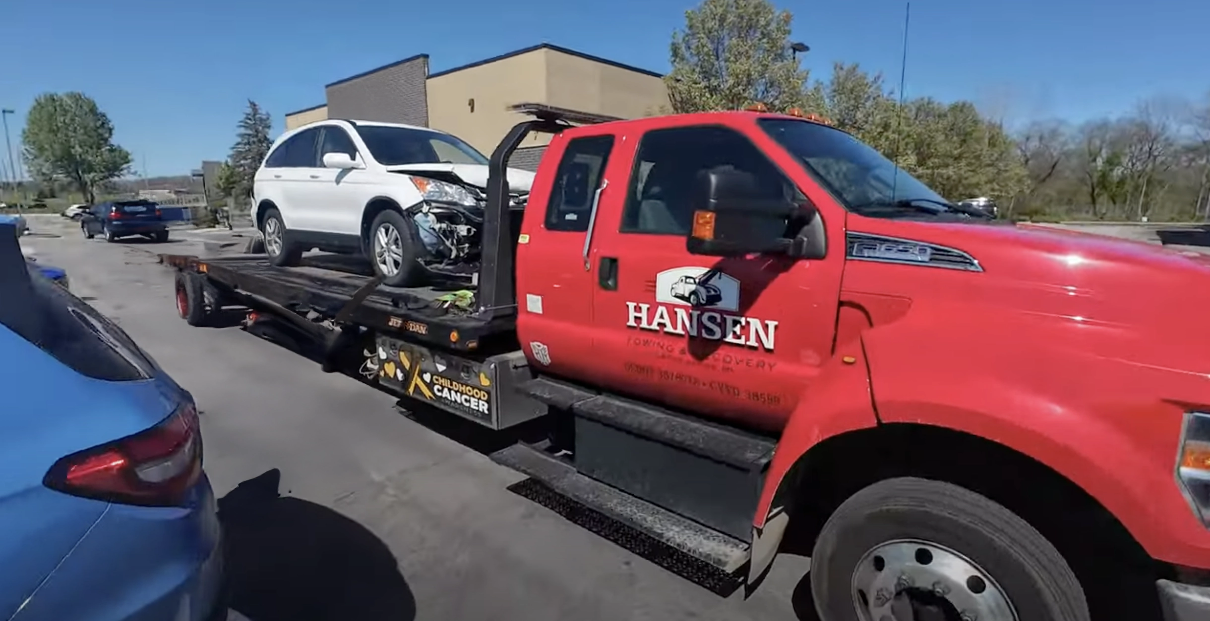 Wrecked SUV being towed on a flat bed tow truck by Hansen Towing in Grand Rapids, MI