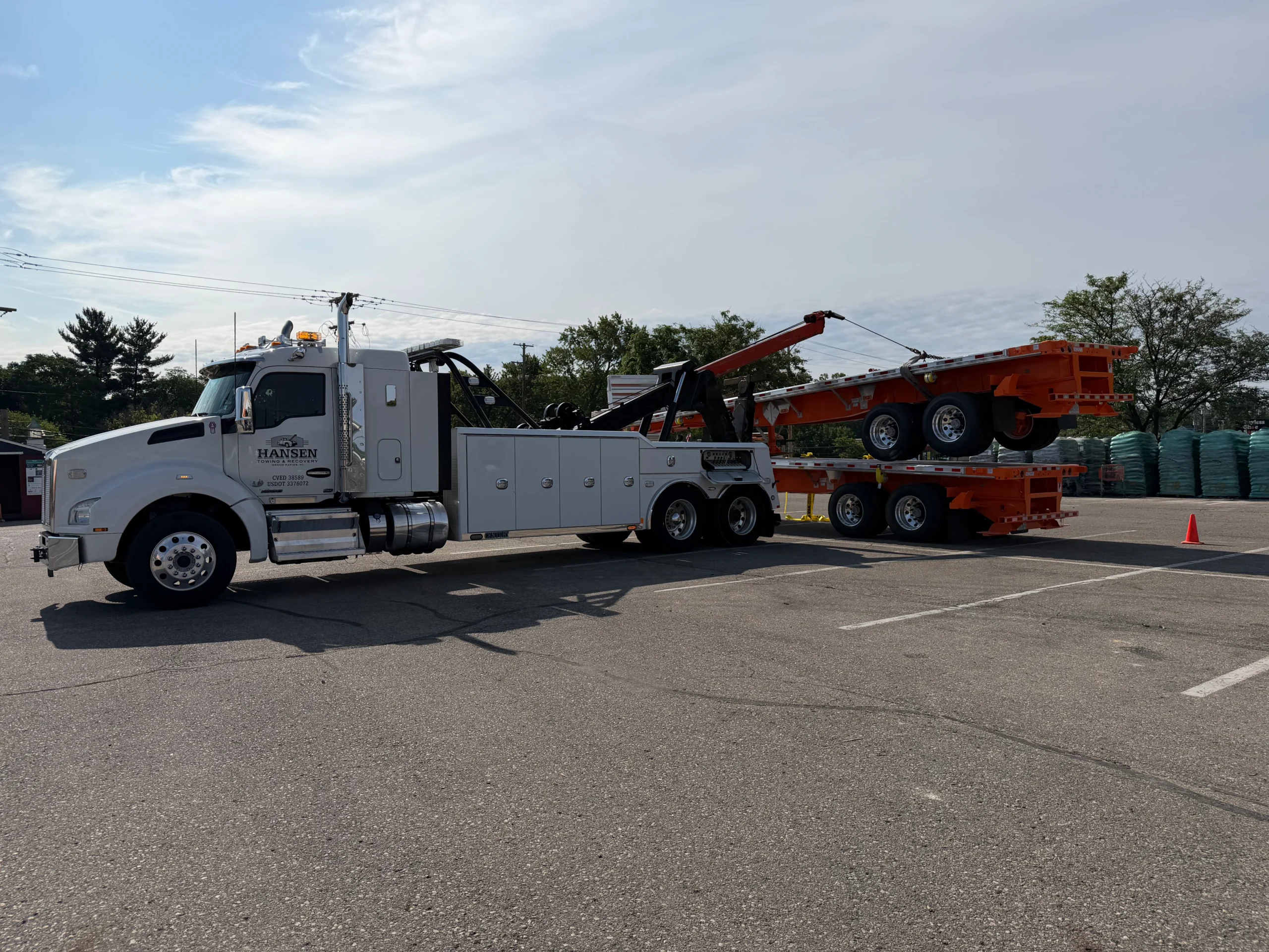 Hansen Towing's heavy-duty wrecker stacking flatbed trailers using the decking (piggybacking) method at a Home Depot on Alpine Avenue in Grand Rapids, Michigan.
